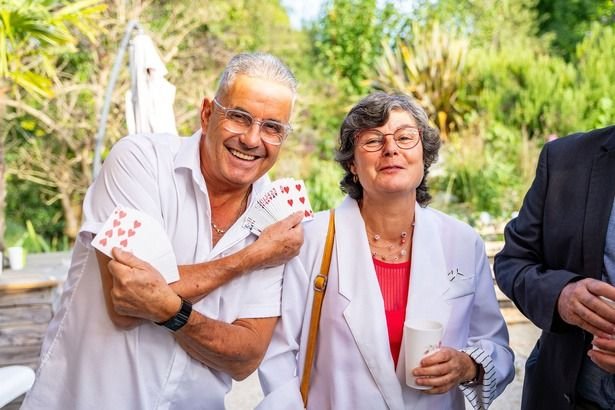 Des invités amusés tenant des cartes après un tour de magie