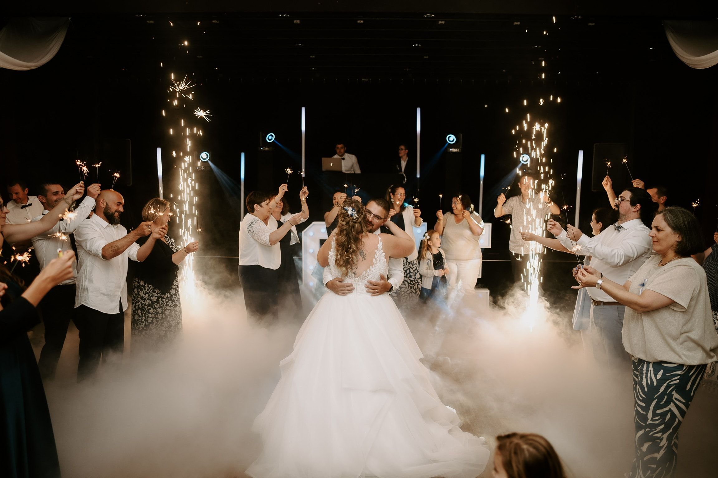 La mariée danse au milieu de ses proches, dans la fumée lourde et les étincelles froides