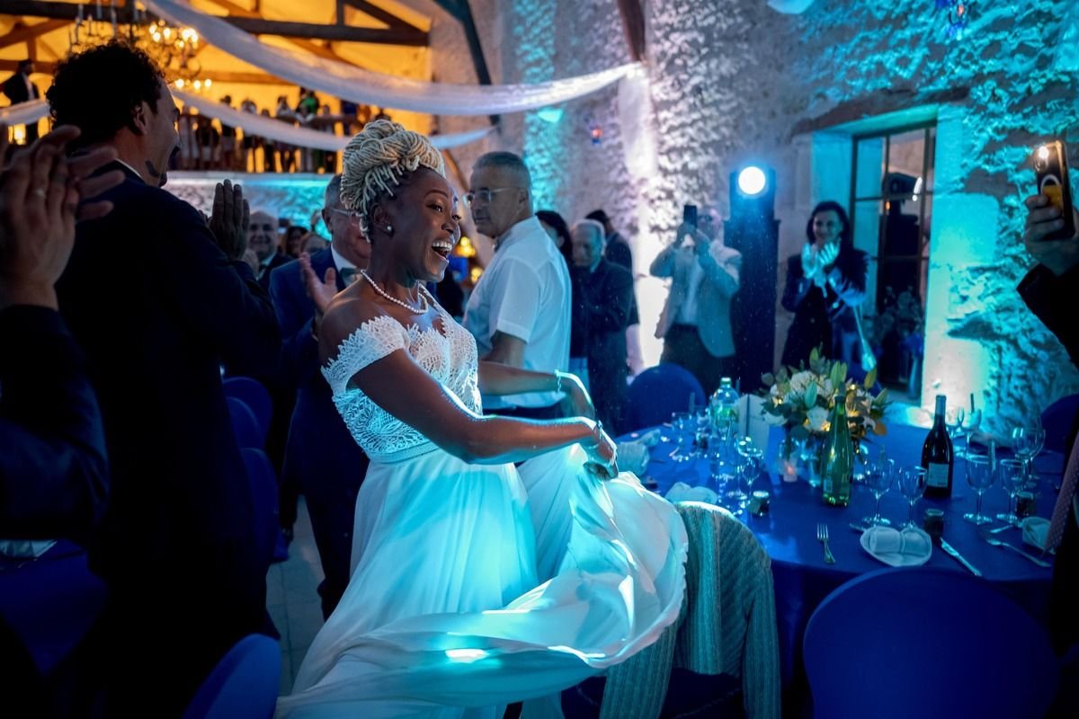 Une mariée rit au milieu de ses invités sous une lumière bleue