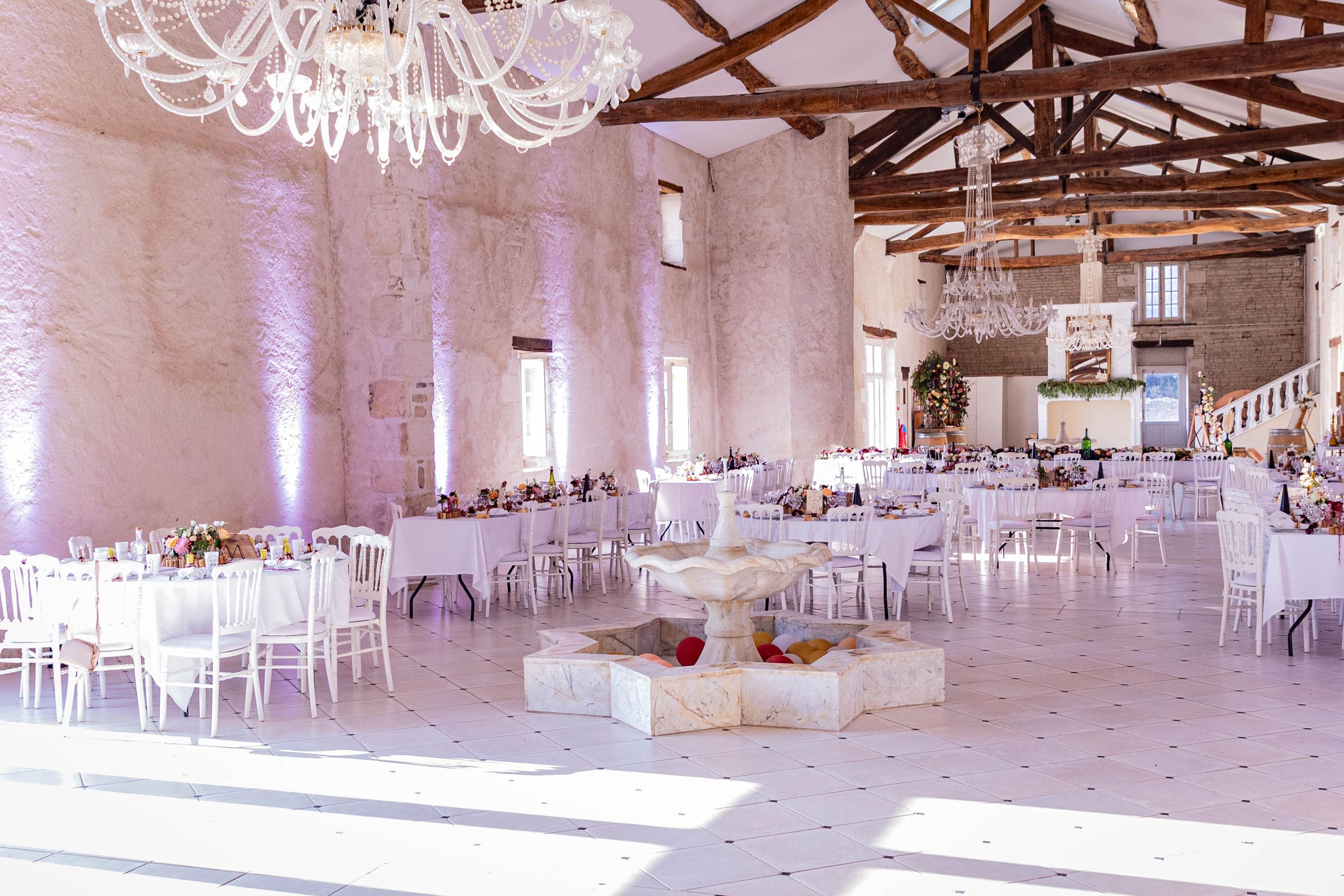 Salle de réception à poutres et lustres, murs mis en lumière par l’éclairage architectural